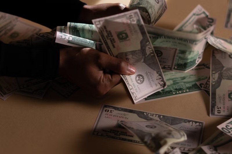 Hands holding US dollar bills over a table